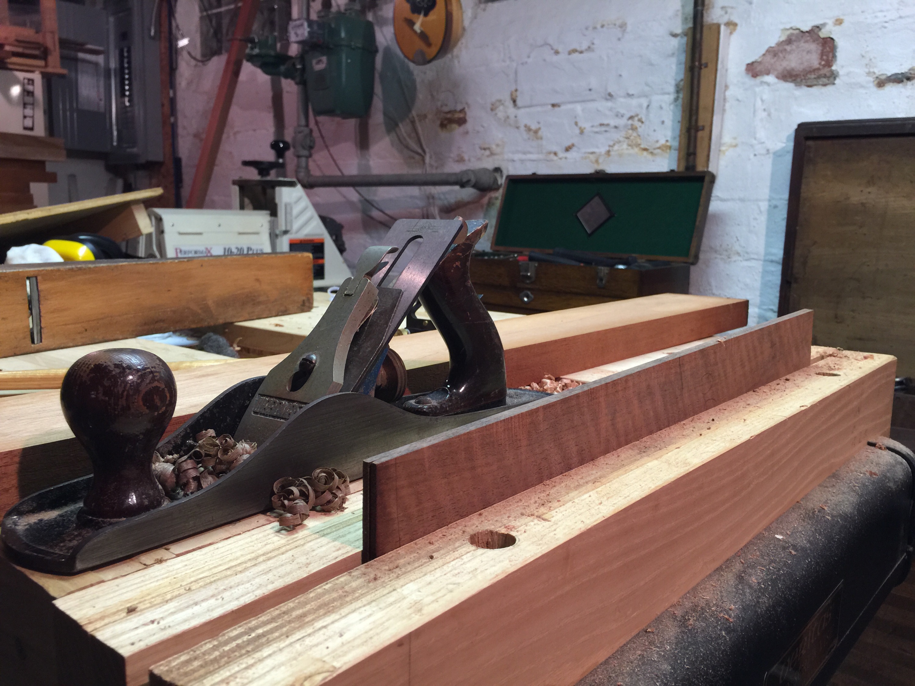 Joining the curly claro walnut back by cutting along the tops of the board with a plane.