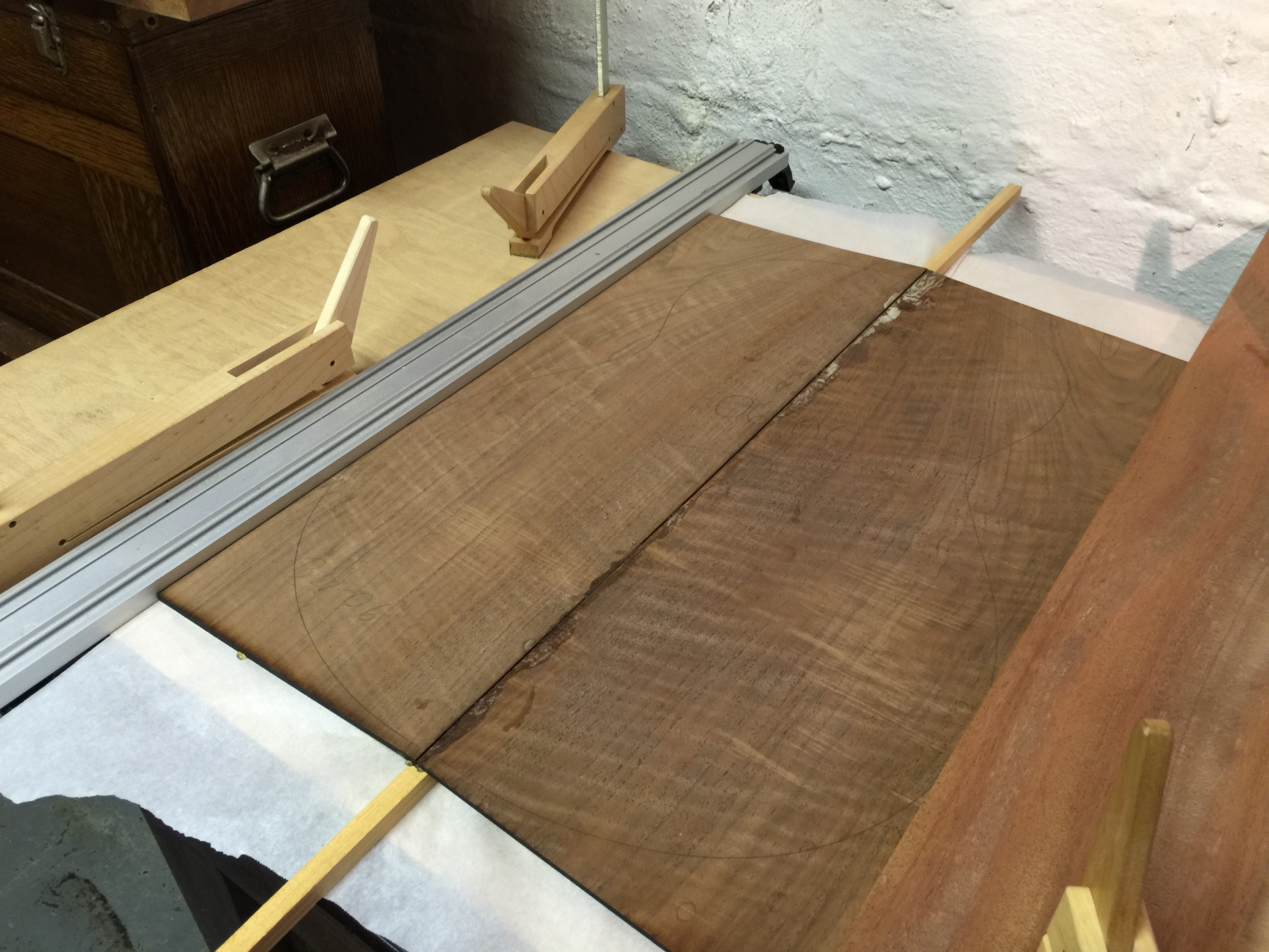 Walnut Back, ready to joint. Wood on one side, and the aluminum on the other serve to contrain the boards horizontally. Two sticks are temporarily inserted under the board pieces to elevate them. Hot hide glue is slathered onto the edge, and then the two boards drop into place with gravity.